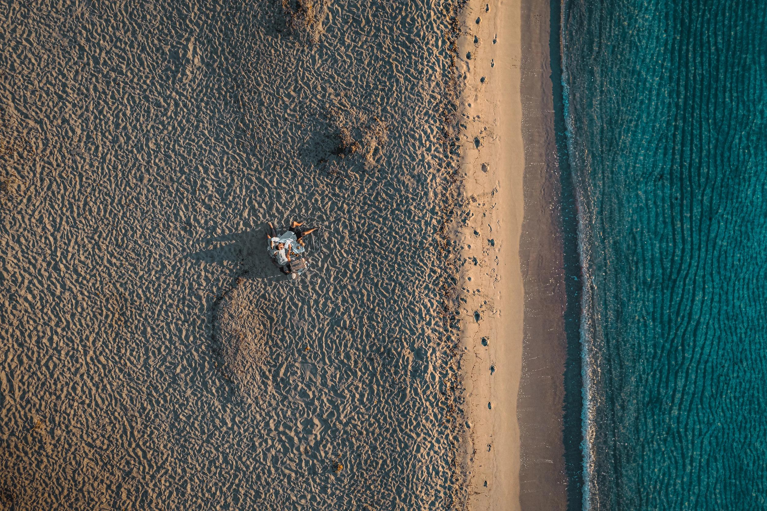 Vue de drone d'un homme qui est allongé sur le sable en face de la mer aux alentours des Oliviers de Palombaggia en Corse-du-Sud.
